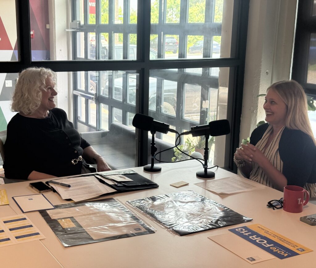 two women chatting at a table with microphones