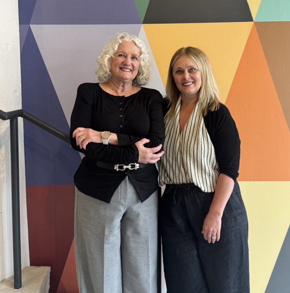 two women posing in front of colorful wall